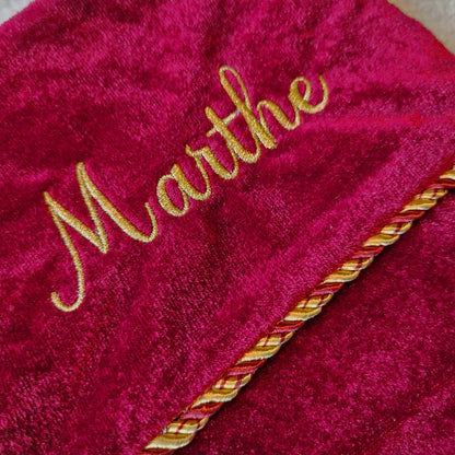 Eksklusiv rød julestrømpe i fløyel med personlig brodert navn “Thomas”. Dekorert med elegant gullfrynse og hengende på juletre med julelys og pynt. Eventyrprint.no – perfekt personlig julestrømpe i fløyel til jul. Nærbildet