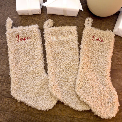 Beige teddy julestrømpe med personlig brodert navn “Jostein”. Myk og fluffy julestrømpe hengende ved juletreet, perfekt til julegaver og pynt. 20 % rabatt hos Eventyrprint.no – design din egen julestrømpe med navn. 3 sokker