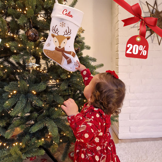 Hvit julestrømpe med brun reinsdyrmotiv, snøfnugg og brodert personlig navn på mansjetten.