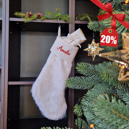 Hvit luksus julestrømpe i myk faux fur med personlig brodert navn “Amalie”. Elegant og fluffy julestrømpe hengende på juletre med 20 % rabatt hos Eventyrprint.no – perfekt personlig julegave til barn og voksne.
