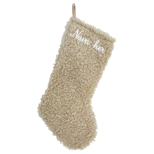 Beige julestrømpe i mykt teddy-stoff, med personlig brodert navn øverst.