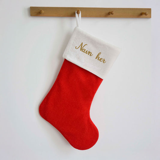 Klassisk rød julestrømpe i fløyel med hvit kant, brodert med personlig navn i julefarger.