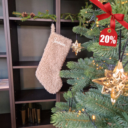 Beige teddy julestrømpe med personlig brodert navn “Jostein”. Myk og fluffy julestrømpe hengende ved juletreet, perfekt til julegaver og pynt. 20 % rabatt hos Eventyrprint.no – design din egen julestrømpe med navn.